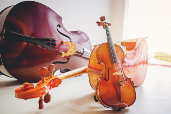 A Double bass, cello, and a violin lying on the floor with a bright background