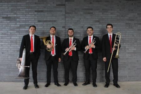 The Bulldog Brass Society standing in front of a gray brick wall